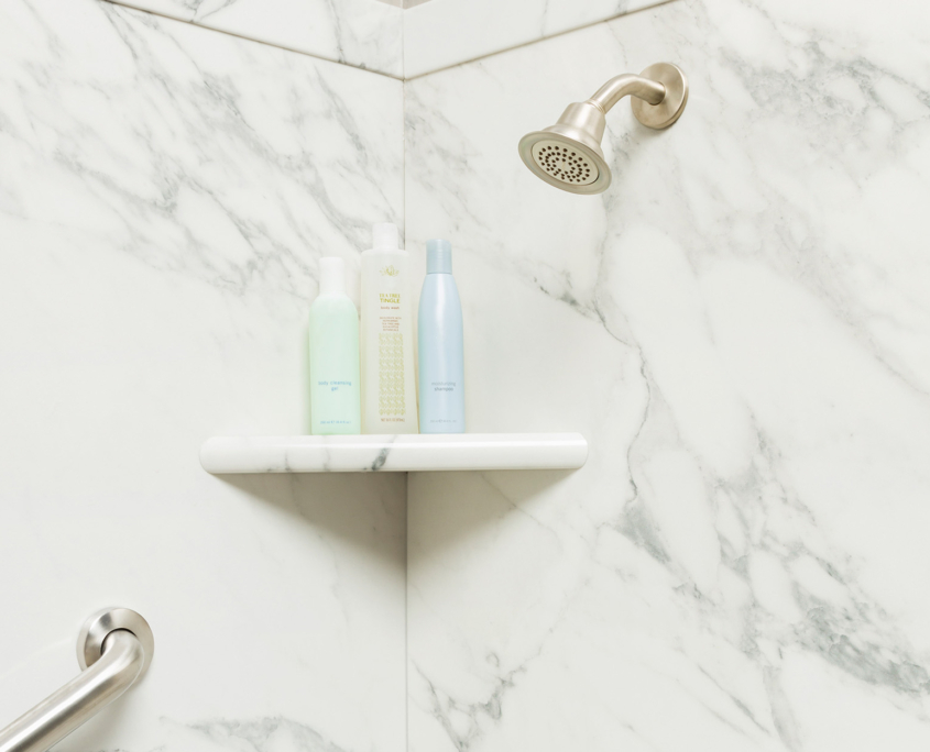 Front view of marble shower shelf with toiletries on it