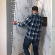 Side view of a man installing a shower wall