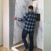 Side view of a man installing shower wall