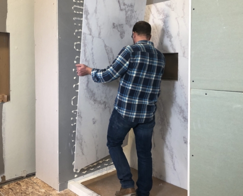Side view of a man installing shower wall